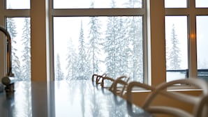 A view through a window with a reflection of a chair and a snowy forest. - New built, modern ski-in/ski-out home with great views of Columbia River Valley (Golden)