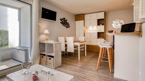 Et moderne køkken med hvide skabe, et spiseområde med hvide stole og en bar med barstole.