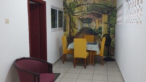 Ein Essbereich mit gelben Stühlen und einem Tisch, einer rotem Tür und Wandmalerei.