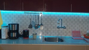 Eine Küche mit Spüle, diversen Küchenutensilien, einer Kaffeemaschine und einem Wasserkocher.