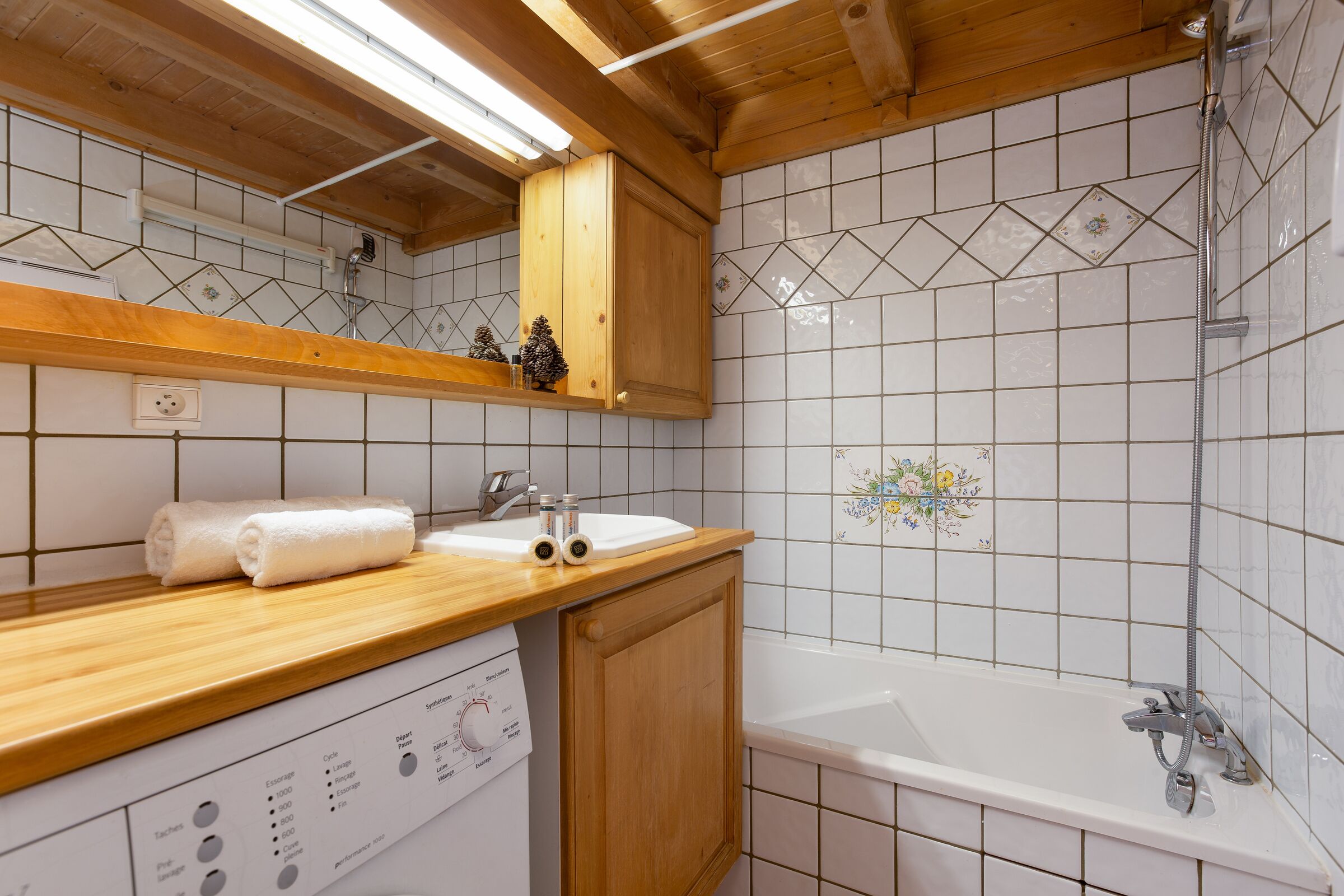 Un baño con tocador de madera, lavabo blanco y bañera.