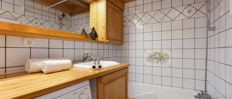 Un baño con tocador de madera, lavabo blanco y bañera.