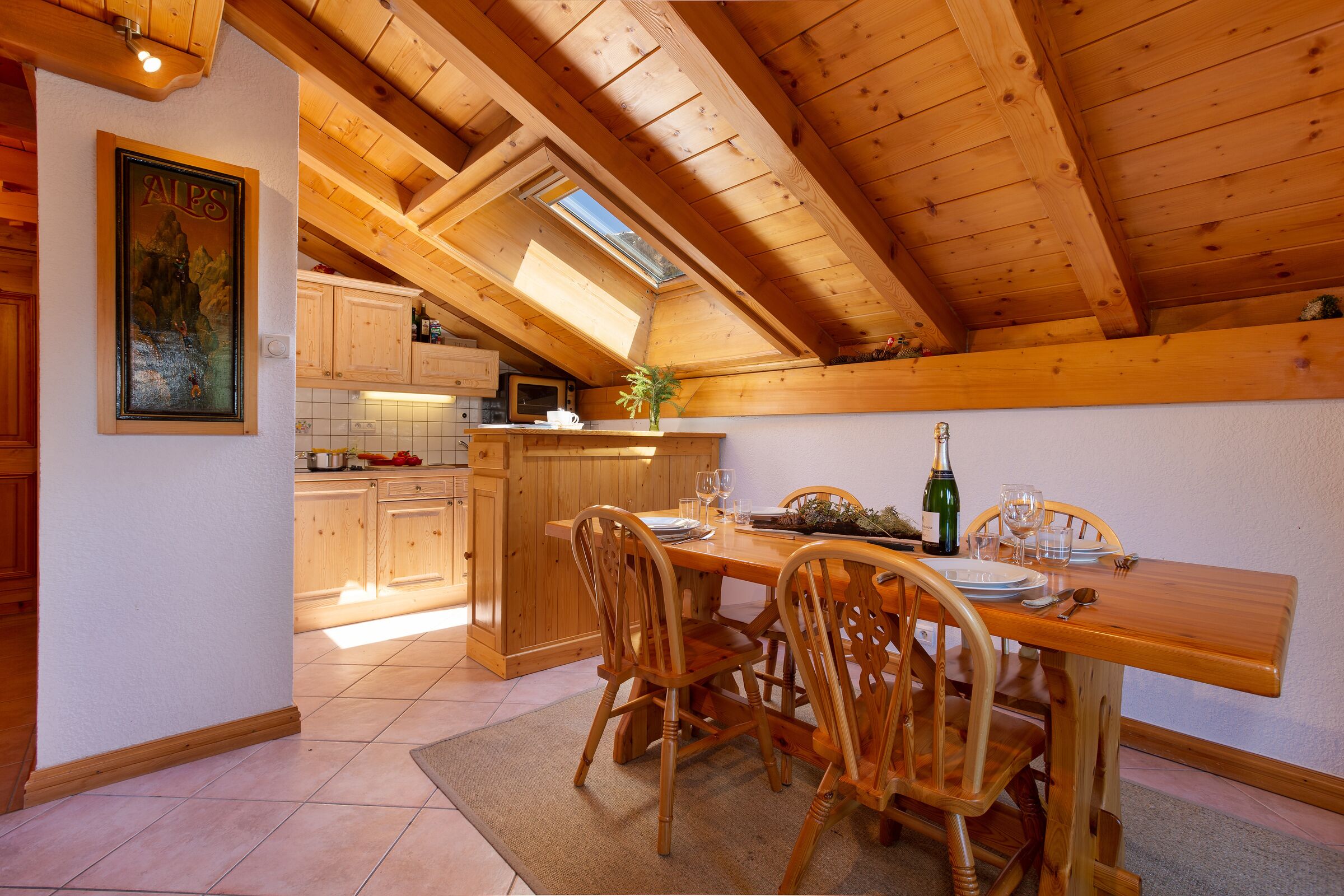 Ein Holztisch mit Stühlen, eine Küchenzeile mit Holzschränken und ein Oberlicht.