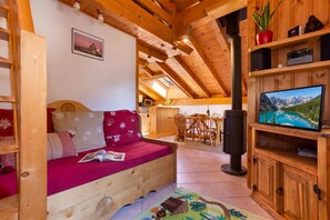 A cozy wooden cabin interior with a sofa, a television, and a dining area.