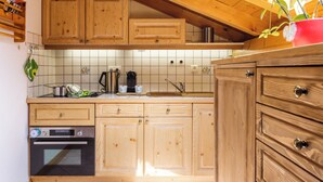Une cuisine avec des meubles en bois, un four en acier inoxydable et une plante en pot rouge.