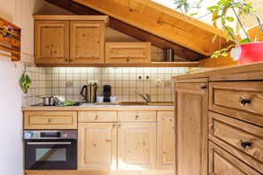 Een keuken met houten kastjes, een roestvrijstalen oven en een rode plant in een pot.