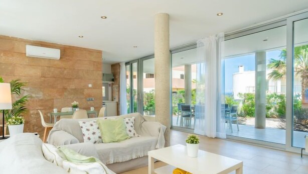 Un salon moderne comprenant un canapé, une table basse et un coin repas avec des chaises.