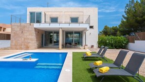 Une maison moderne à deux étages dotée d’une piscine, d’un espace salon extérieur et d’une terrasse.