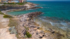 Une zone côtière caractérisée par un terrain rocheux et des eaux d’un bleu limpide.