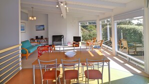 A spacious living area with a wooden dining table, red chairs, a sofa, and a television. - 60 Karbeethong Avenue, Mallacoota (Mallacoota)