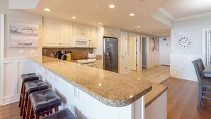 A modern kitchen with white cabinets, a granite countertop, and a stainless steel refrigerator.