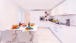 A modern kitchen with white cabinetry, a dining table set with plates and cutlery, and a kitchen island with appliances. - Yellow view apartment - Ronco S/Ascona, Ronco sopra Ascona, Switzerland (Ronco sopra Ascona)