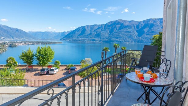 A balcony with a table set for breakfast, overlooking a lake and mountains. - Yellow view apartment - Ronco S/Ascona, Ronco sopra Ascona, Switzerland (Ronco sopra Ascona)