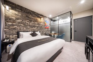 Una habitación de hotel moderna con una pared de ladrillo, una cama con ropa blanca, un escritorio con una silla y una puerta con la leyenda 'HOTEL HERMES'.