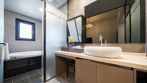 Un baño moderno con un espejo grande, un lavamanos blanco y una bañera.
