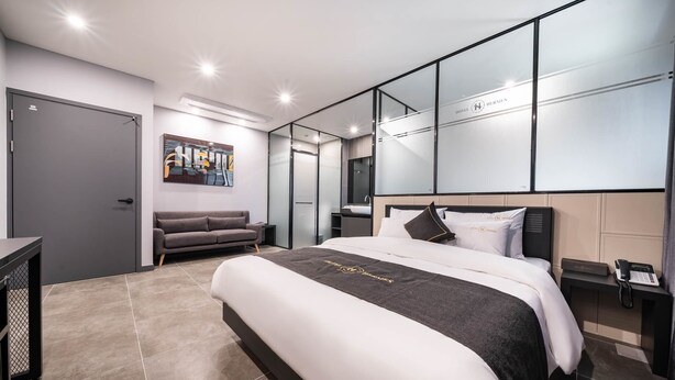 Una habitación de hotel moderna con una cama grande, un sofá, un escritorio y un espejo.