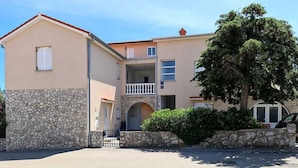 A two-story building with a stone facade, a balcony, and a tree in front. - Apartment Mihalić (10070-A1) (Silo - island Krk)