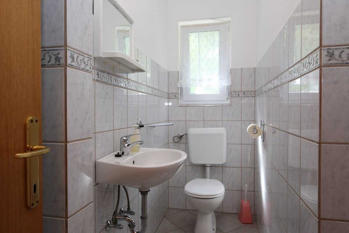 A bathroom with a sink, toilet, and window.