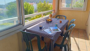 A balcony with a table set for two, featuring a patterned tablecloth, two chairs, and a bottle of juice. - Résidence Les Sangliers by Interhome (Saint-Raphaël)