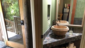 A bathroom with a large, round, terracotta sink, a mirror, and a tiled countertop. - Maui What A Wonderful World B and B Hawaii  (Kihei)