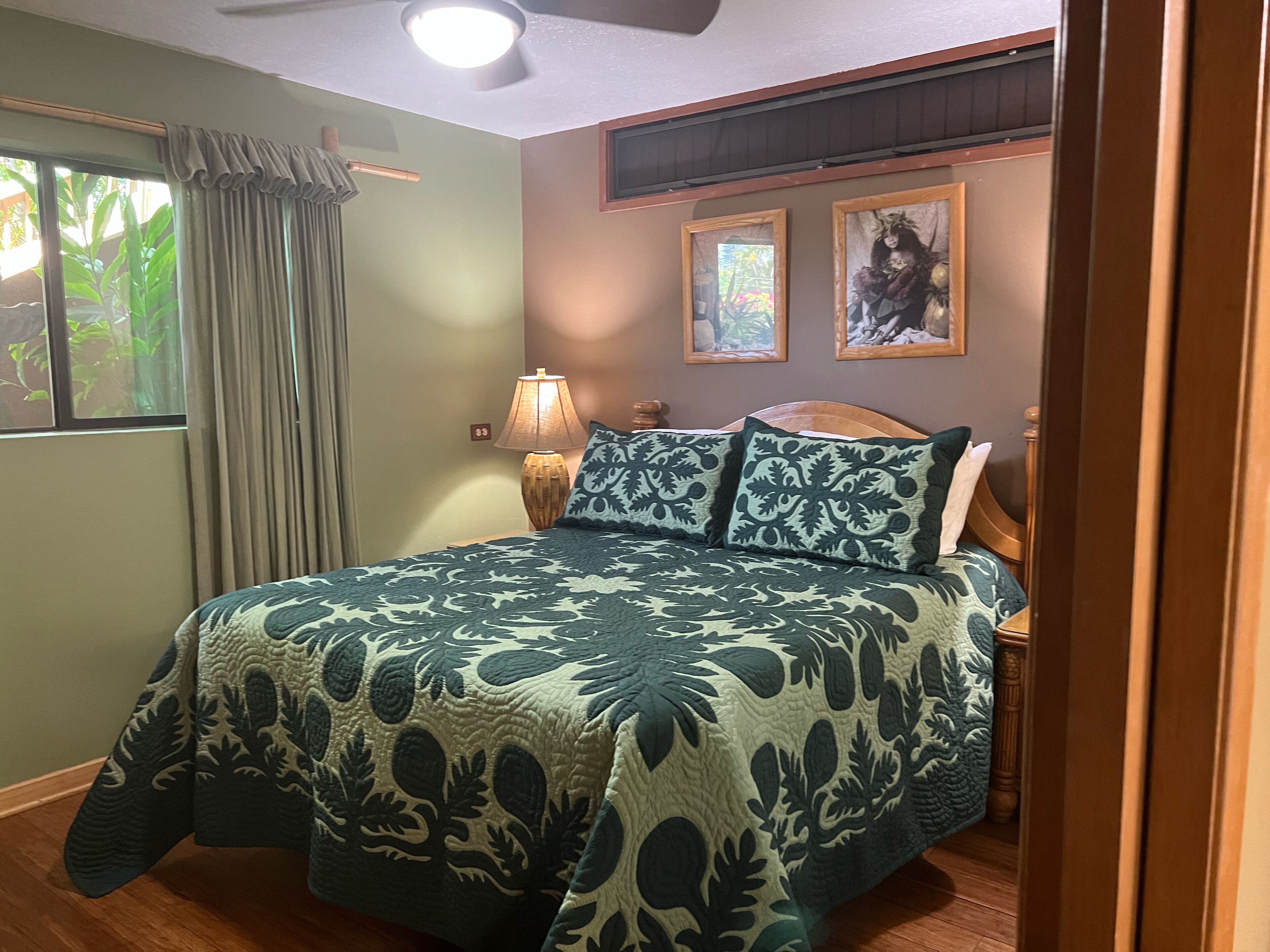 Une chambre à coucher avec un lit, une table de chevet, une lampe et deux tableaux encadrés accrochés au mur.