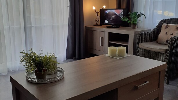 Una sala moderna con una mesa de centro de madera, un televisor y un sofá de mimbre.