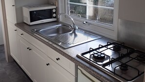 Una cocina moderna con armarios blancos, microondas, pileta y estufa a gas.