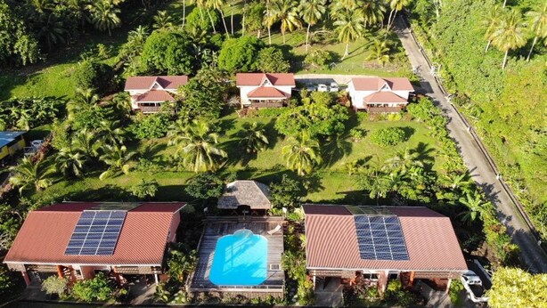 Un resort con varias edificaciones, cada una con paneles solares en los techos y una piscina.