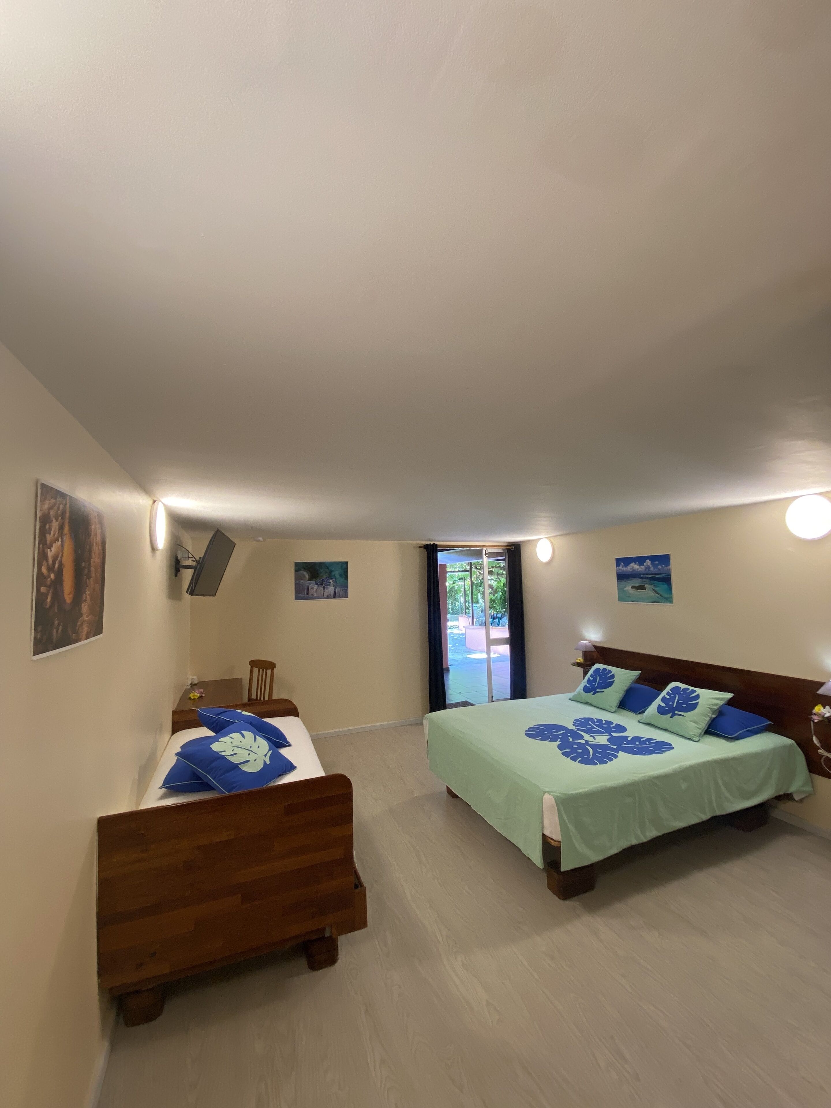 Une chambre avec deux lits en bois, une petite table et une chaise.
