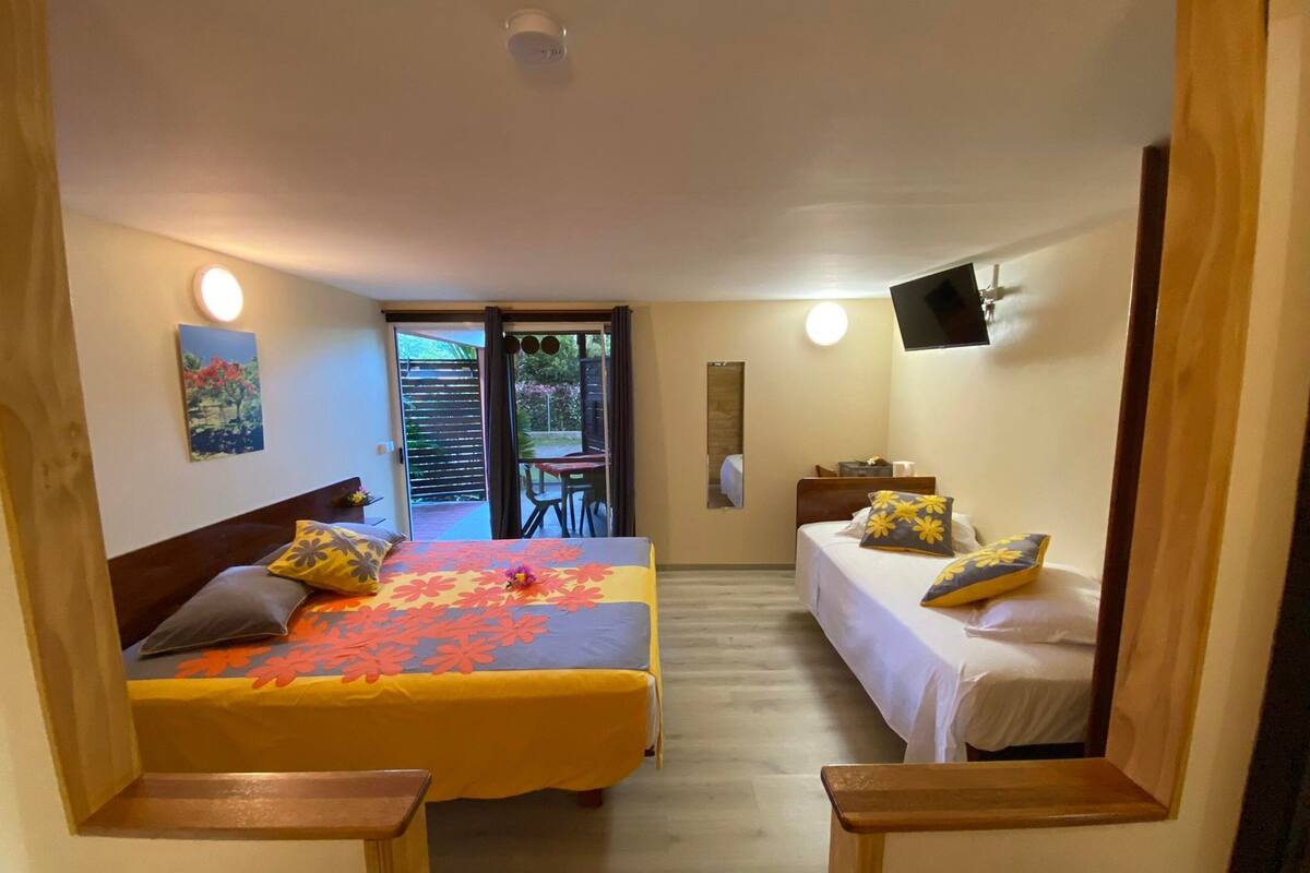 A hotel room with a bed, a sofa, a TV, and a balcony with a table and chairs.