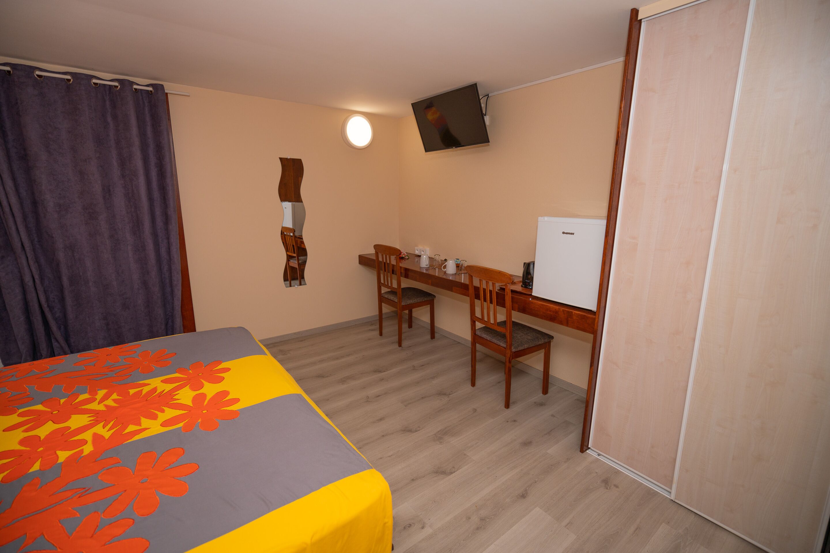 Une chambre comprenant un lit, un bureau, une chaise, une télévision et une armoire.