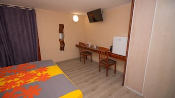 Une chambre comprenant un lit, un bureau, une chaise, une télévision et une armoire.