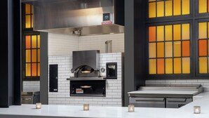 A modern kitchen with a built-in oven, white tiled backsplash, and a countertop with candles. - Canopy by Hilton Ithaca Downtown (Ithaca)