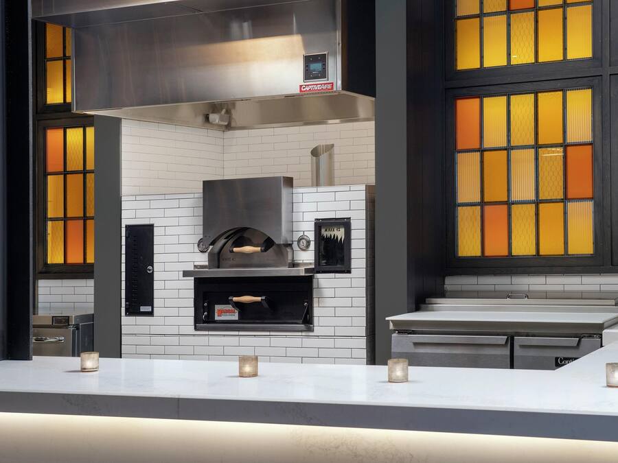 A modern kitchen with a built-in oven, white tiled backsplash, and a countertop with candles.