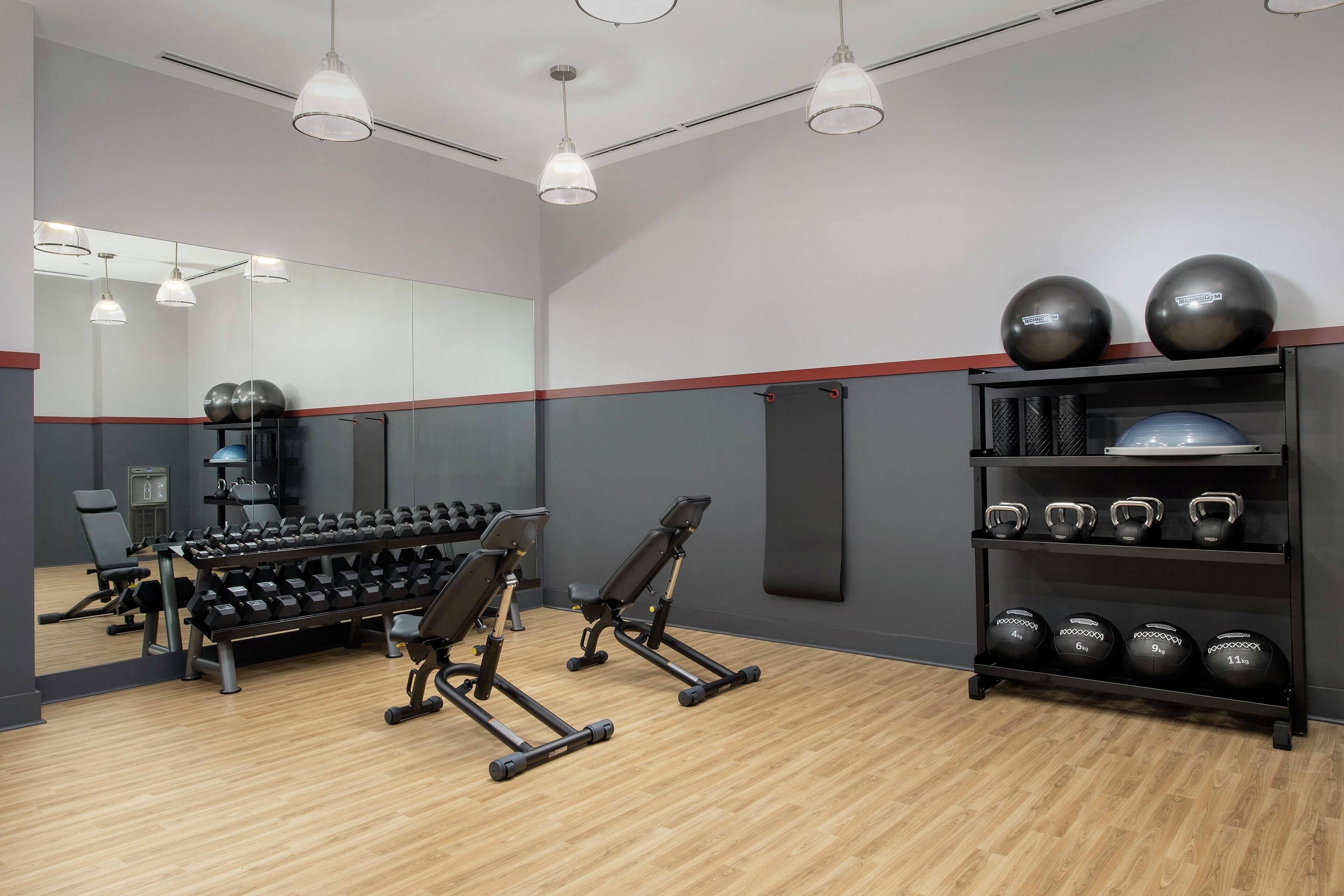 Une salle de sport équipée de matériel d’exercice, notamment des haltères, des kettlebells et un banc.