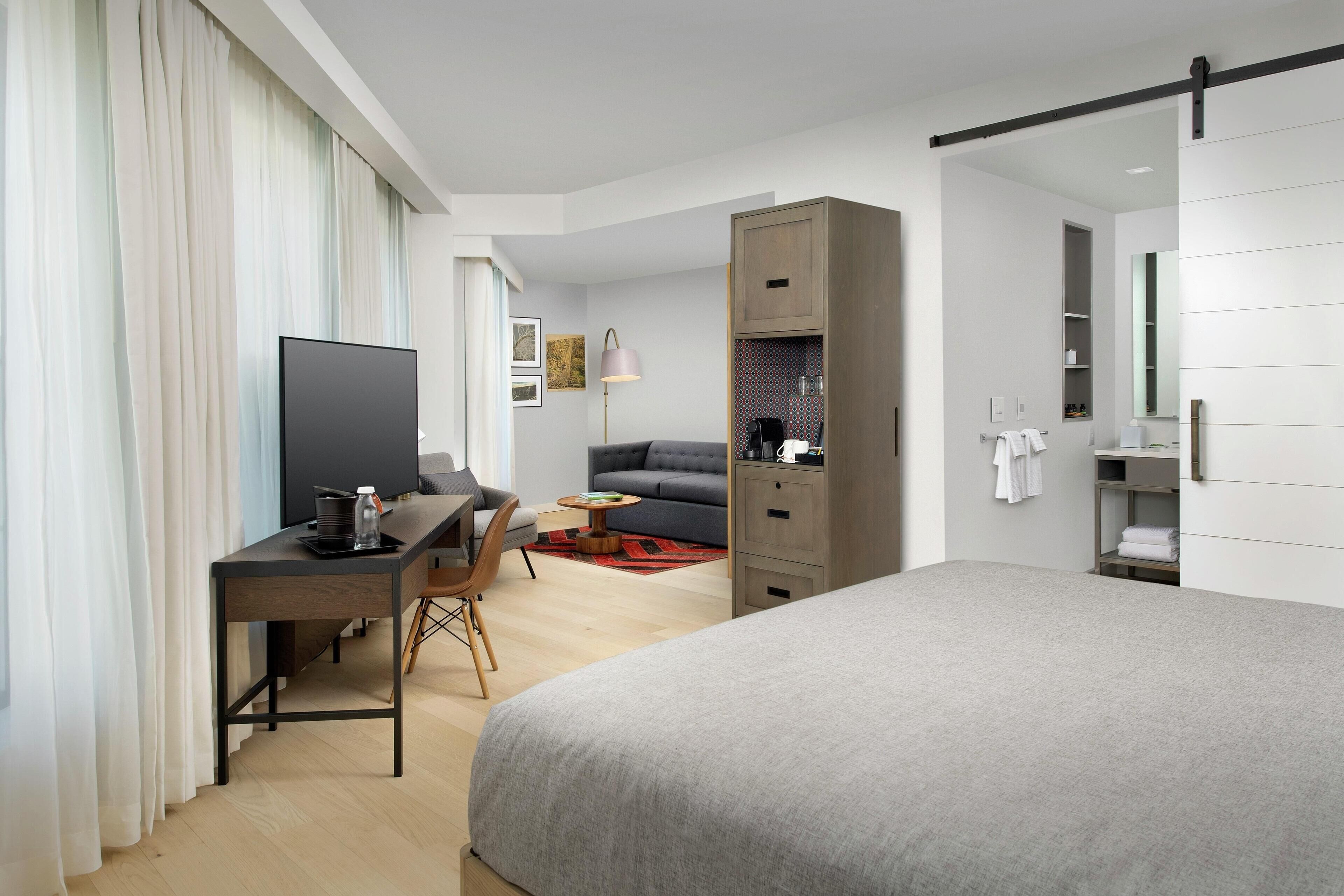 Een moderne hotelkamer met een groot bed, een bureau met een computer, een bank en een kledingkast.