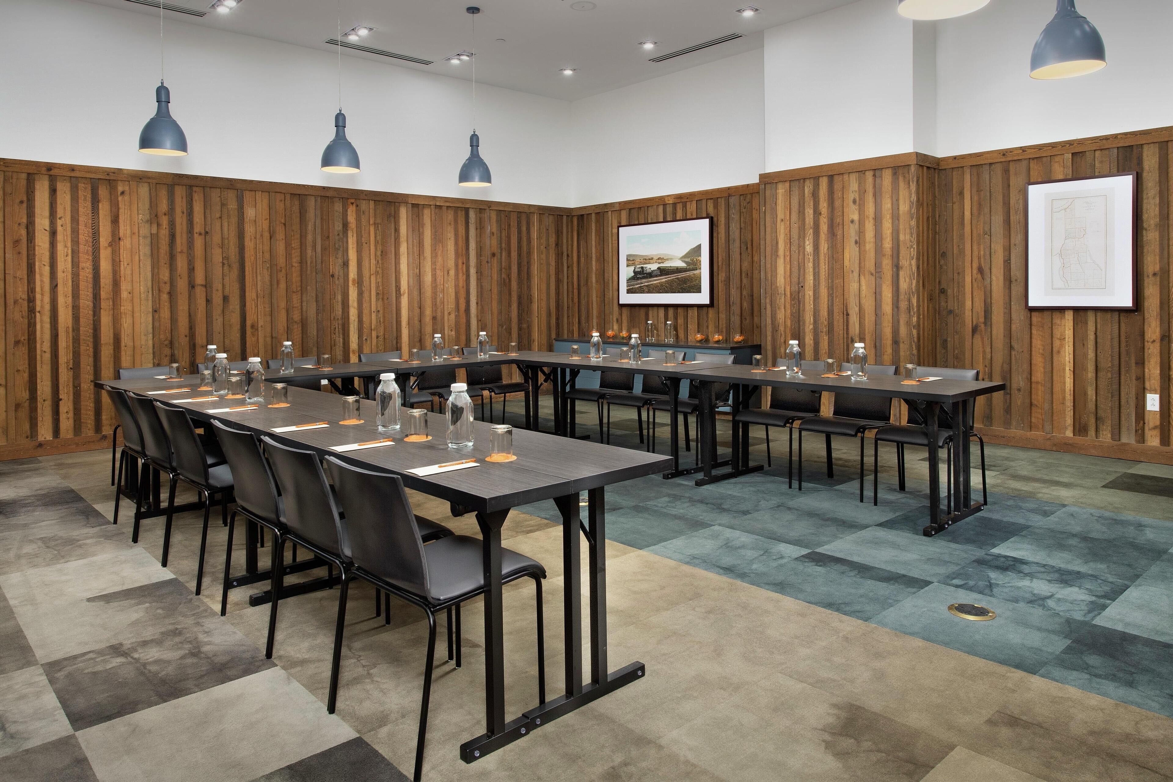 Une salle de conférence avec une longue table, des chaises et des luminaires suspendus.
