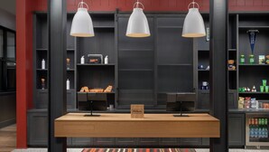 A hotel reception desk with a 'Hilton Honors' sign, three pendant lights, and a patterned rug. - Canopy by Hilton Ithaca Downtown (Ithaca)