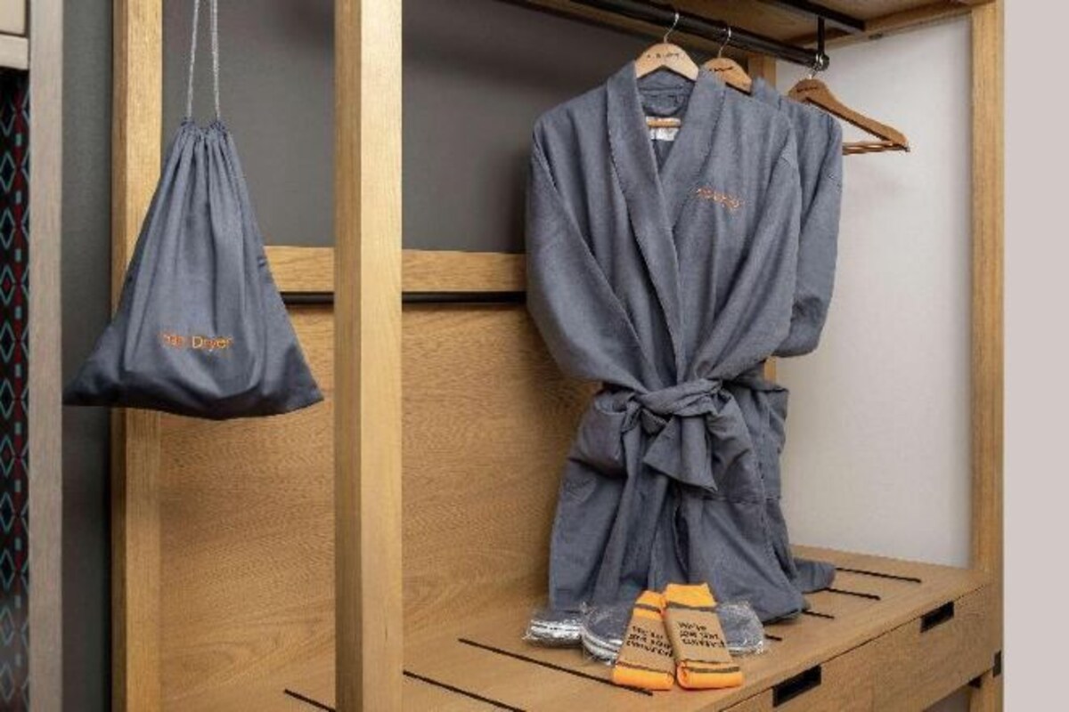 A wooden bench with a robe and slippers, and a hanging bag.