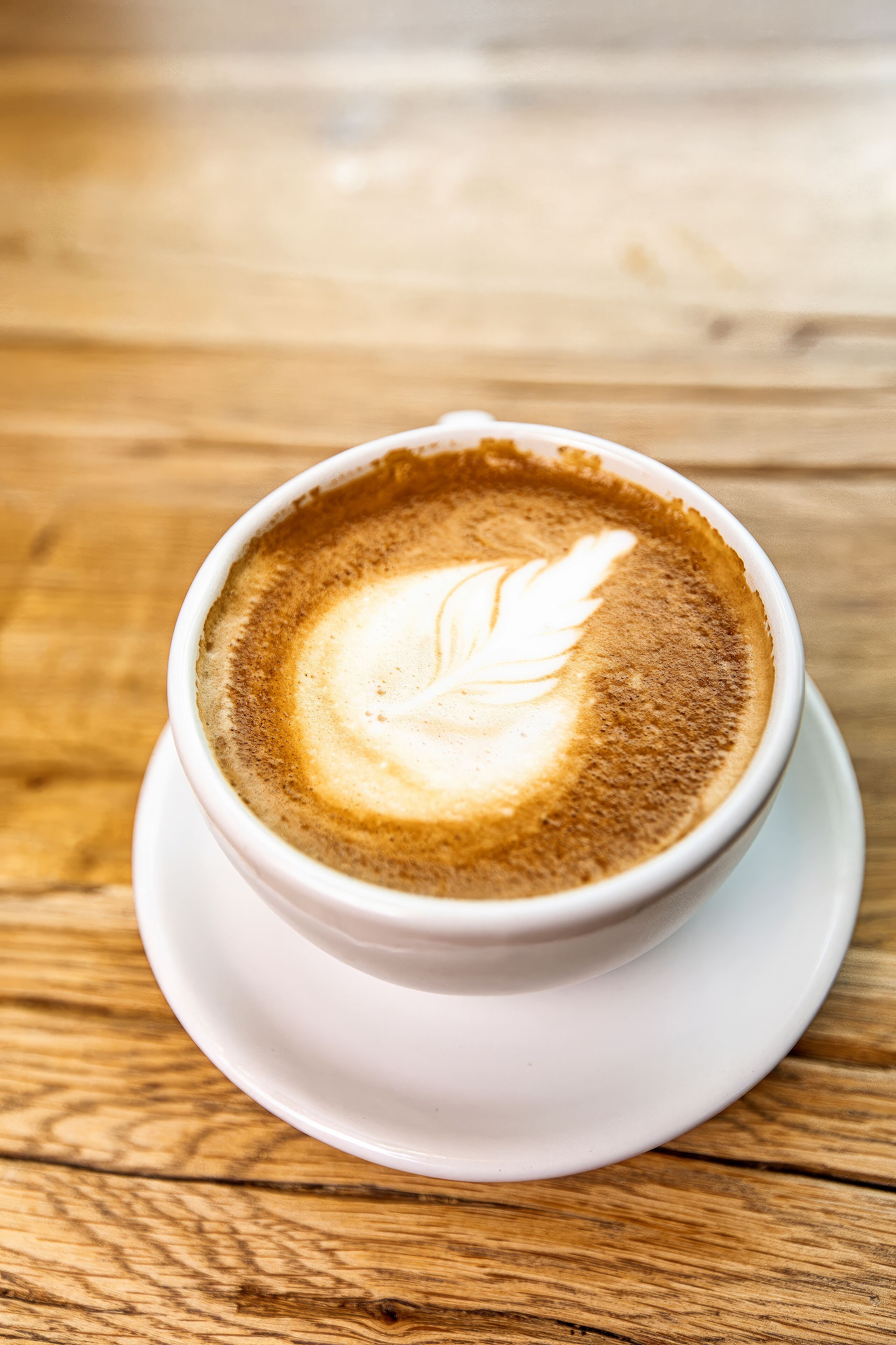 A cup of coffee with latte art on a wooden table.