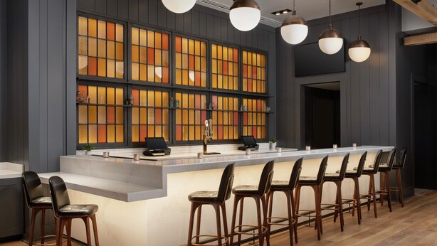 A modern kitchen with a central island, bar stools, pendant lighting, and a large window with stained glass. - Canopy by Hilton Ithaca Downtown (Ithaca)