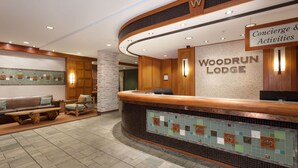 Aula, jossa on puinen vastaanottotiski, kyltti, jossa lukee ”Woodrun Lodge”, sekä oleskelualue, jossa on sohva ja nojatuoleja.