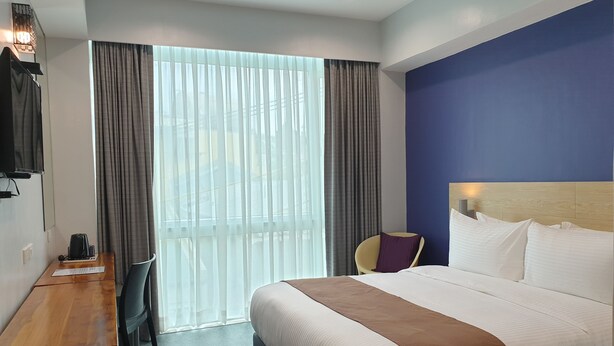 Une chambre d’hôtel avec un lit, un bureau, une chaise et un téléviseur.
