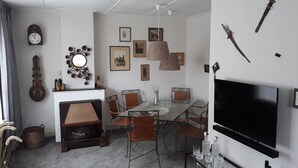 A living room with a fireplace, dining table, chairs, a TV, and various wall decorations. - nice cozy home (Sint-Annaland)