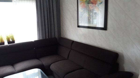 A dark-colored sofa against a white wall with a framed picture.
