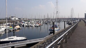 A marina with numerous boats docked along a paved walkway. - nice cozy home (Sint-Annaland)
