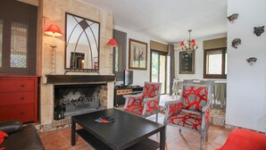 Ein Wohnzimmer mit Kamin, roten und weißen gemusterten Sesseln, einem schwarzen Couchtisch und einem roten Sofa.