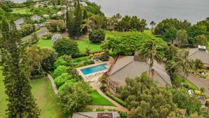 An aerial view of a residential area with a swimming pool, lush greenery, and a view of the ocean. - Pali Ke Kua 216 Amazing Panoramic View, idyllic retreat (Pinceville)