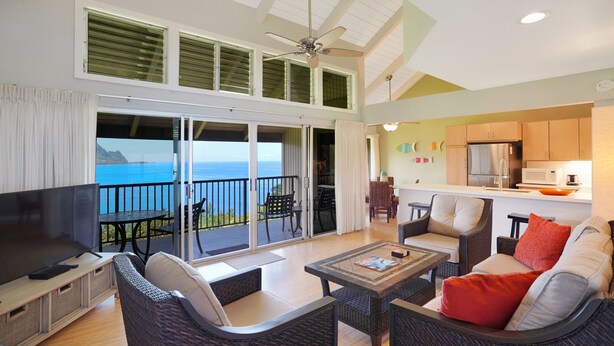 A spacious living area with a balcony overlooking the sea, furnished with wicker furniture and a flat-screen TV. - Pali Ke Kua 216 Amazing Panoramic View, idyllic retreat (Pinceville)