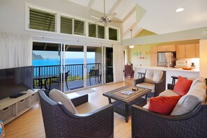 Relax in this spacious living area with a high ceiling and ceiling fan. Enjoy the ocean view from the balcony through the large sliding glass door.